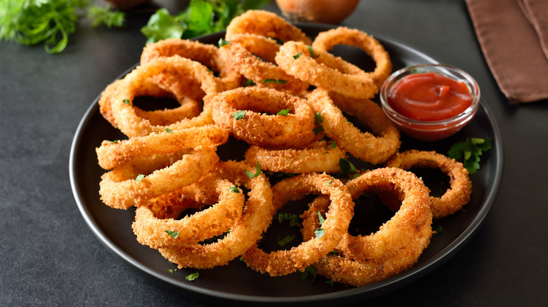 Onion rings on a plate with ketchup.
