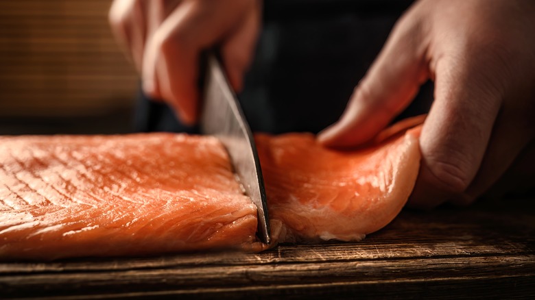 Knife cutting fillet of salmon