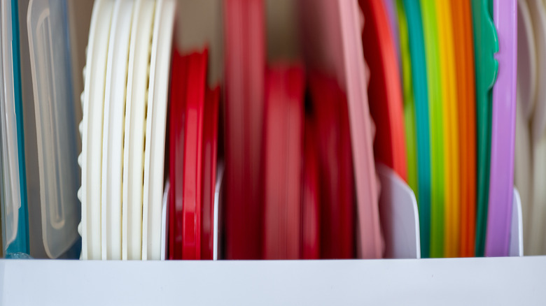 Plastic food container lids in many colors sit separated into slots