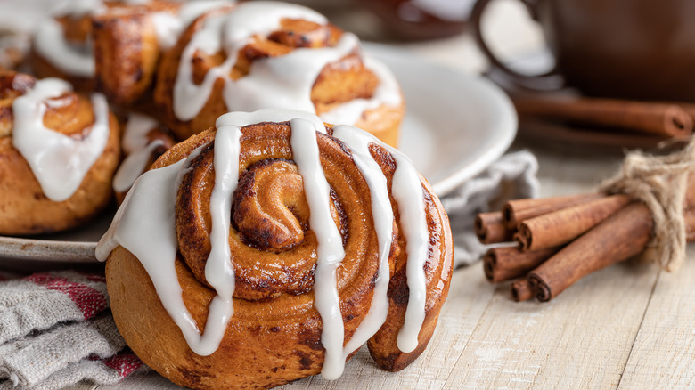 cinnamon rolls on a plate next to a bundle of cinnamon sticks