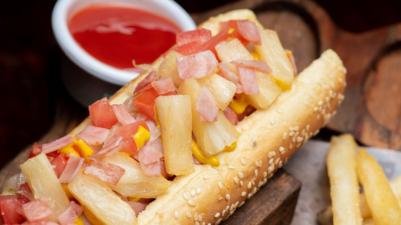 hot dog in bun topped with pineapple and onion