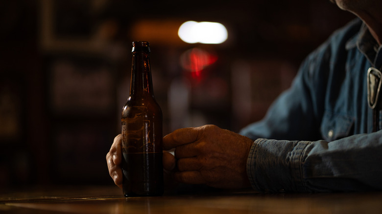Person drinking beer in a saloon setting.