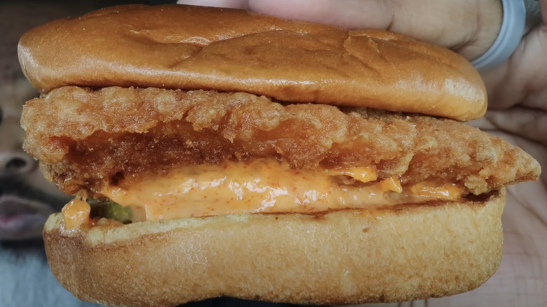 Hands holding the Spicy Flounder Fish Sandwich from Popeyes