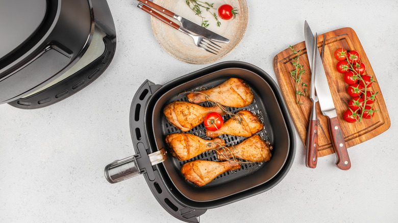 Chicken and a tomato in an air fryer basket