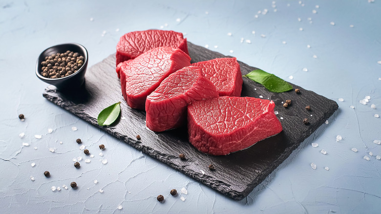 Cuts of lean steak on a wooden chopping board