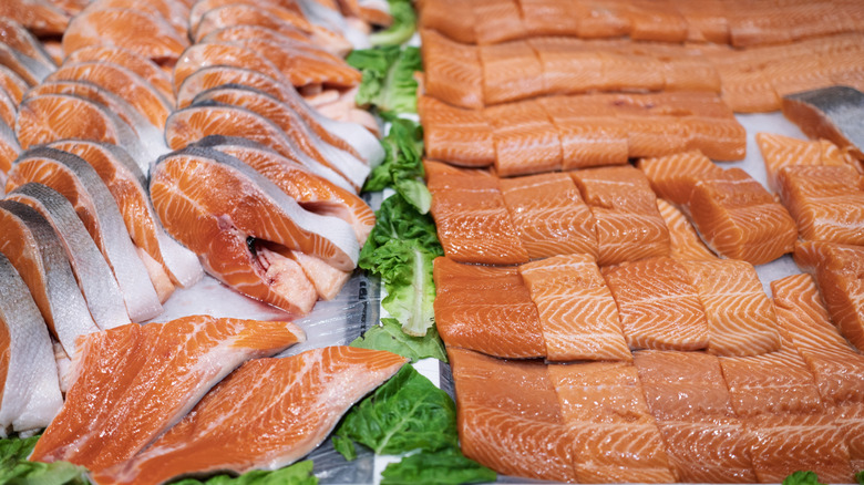 Raw salmon steaks and salmon fillets sit in a display case.