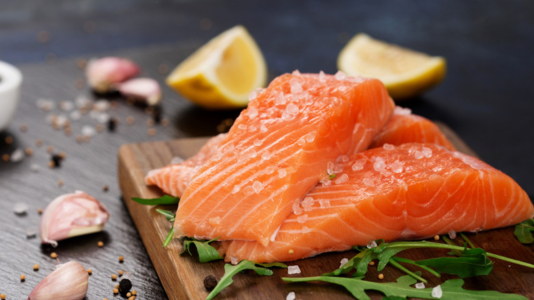 Raw salmon fillets are sprinkled with coarse ground salt and lemon.