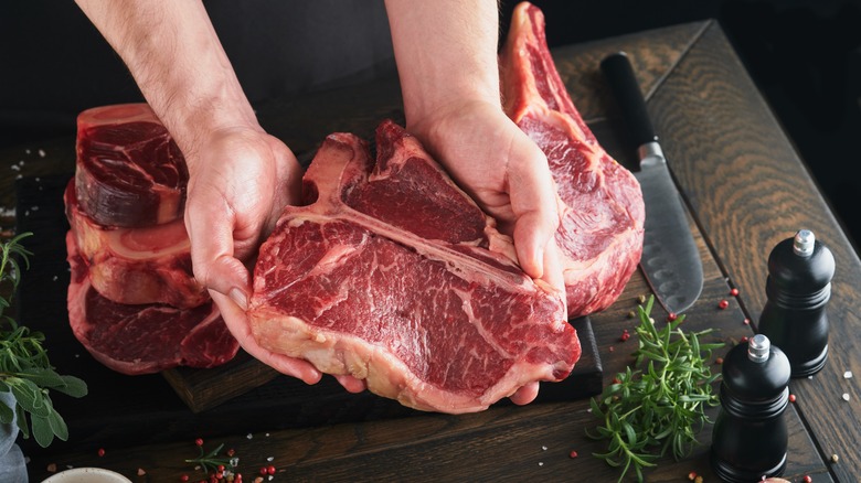 Person holding raw steak 
