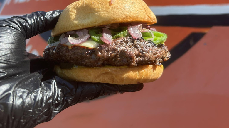 A gloved hand holding the Bun B burger