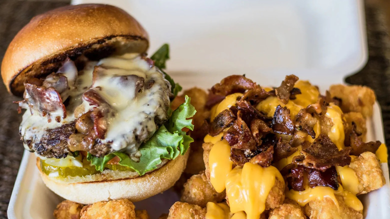 The Cheeseburger in a to-go container with tots