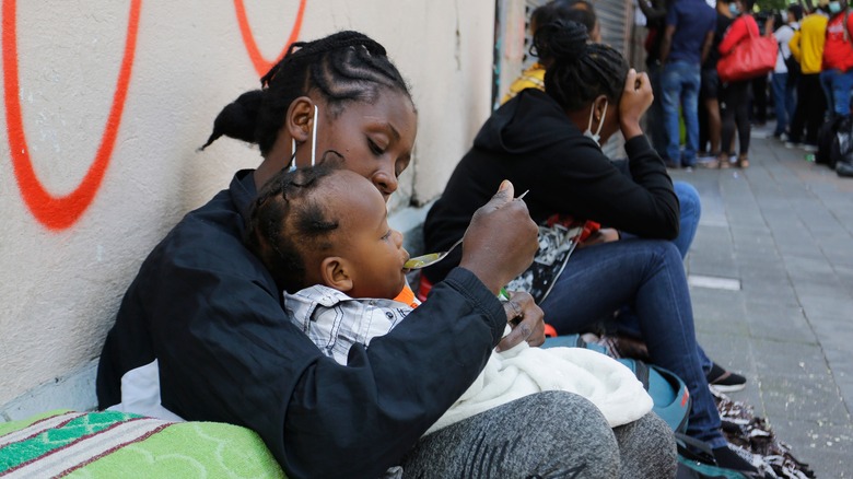 Haitian woman feeding her child on the street