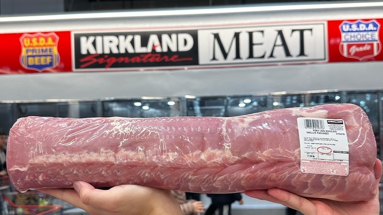 A woman holds up a whole Costco pork loin in vacuum sealed plastic
