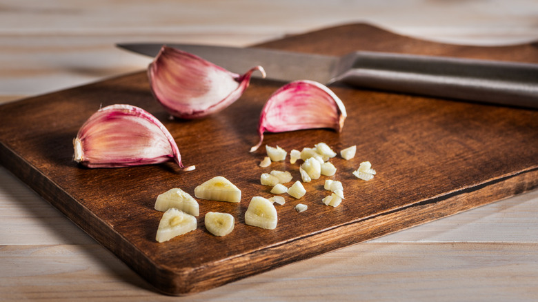 Garlic on a cutting board, some chopped and some still whole
