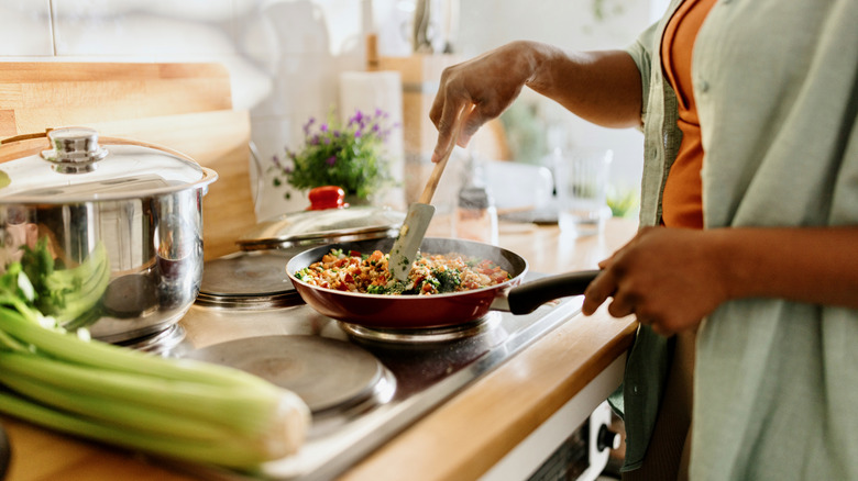 Person cooking vegetables on stove.