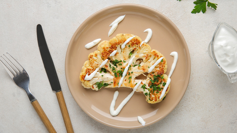 A grilled cauliflower steak drizzled with yogurt.