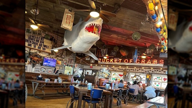 Joe's Crab Shack interior showing patrons and a large great white shark decoration hanging from the ceiling
