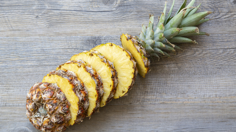 Sliced pineapple sits in rings arranged on a wooden tabled