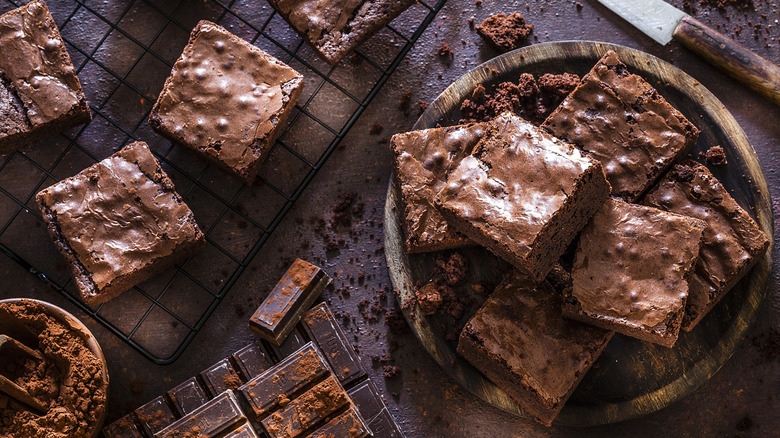 A bowl of brownies, a chocolate bar, and brownies on a cooling rack.
