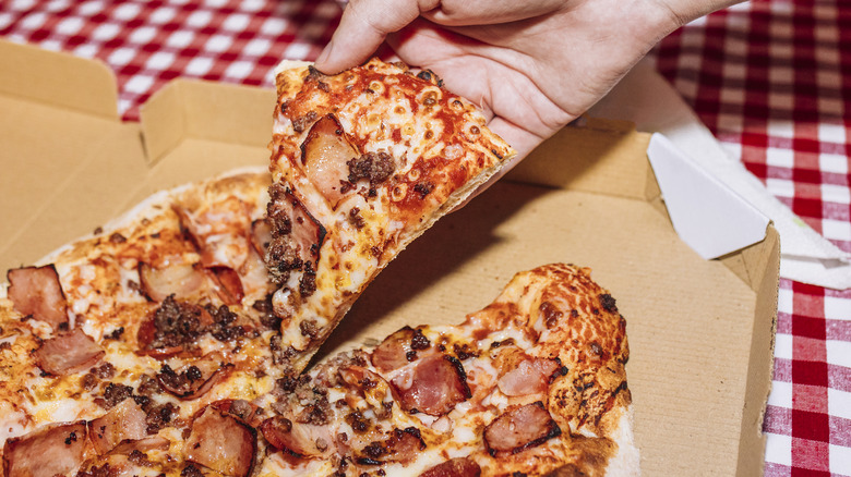 A piece of delicious pizza being pulled from a pizza box