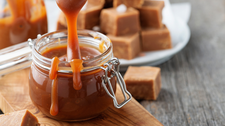 Homemade caramel sauce in a glass jar with spoon