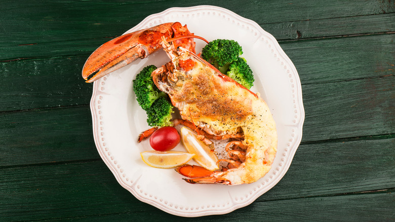 Lobster thermidor on white plate with broccoli and lemon