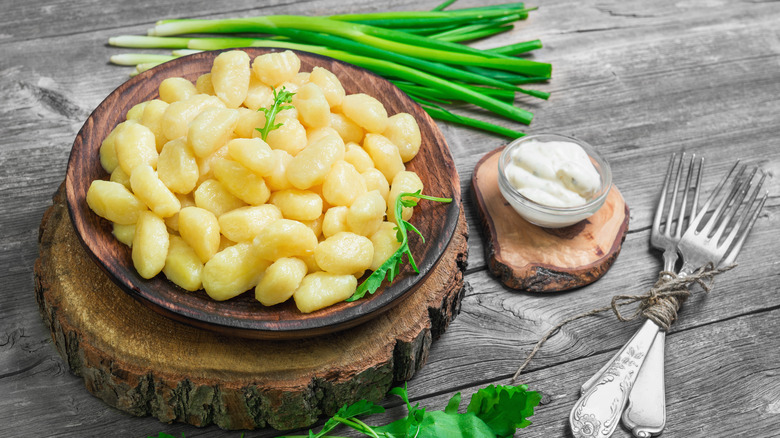 Potato gnocchi on plate with creamy dressing and scallions