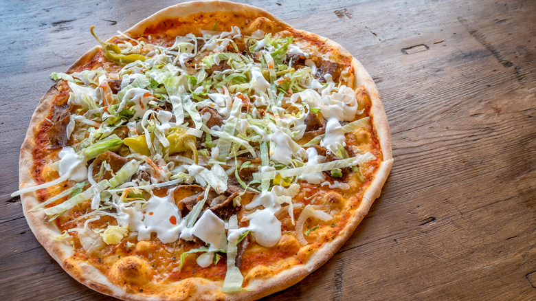 A kebab pizza on a wooden table