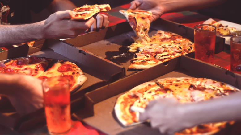 A group of people sharing several pizzas on one table
