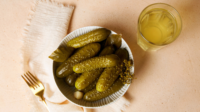 dill pickles with glass of pickle juice