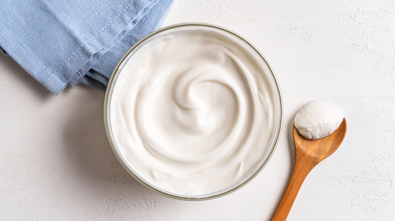 Bowl of plain yogurt with wooden spoon