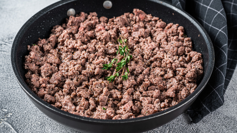 Skillet of cooked ground beef with garnish