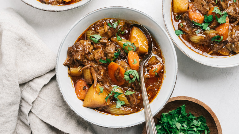 Bowl of beef stew with carrots, potatoes, and herbs