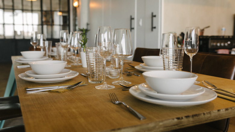 Wooden table with white dishes set for a multi-course meal