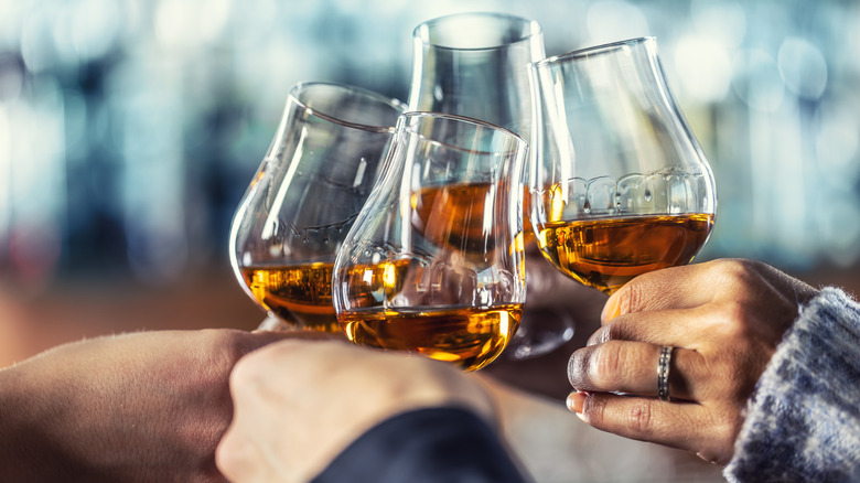 Glasses of a caramel-colored drink clinking together in a toast