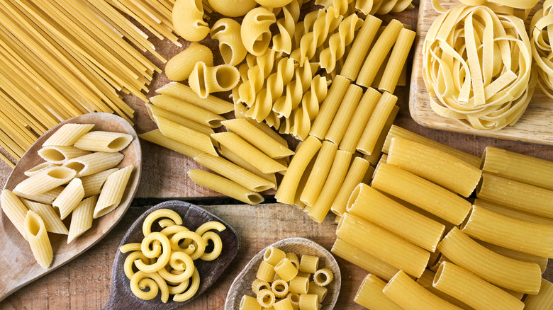 A table is covered with different types of pasta of all shapes and sizes