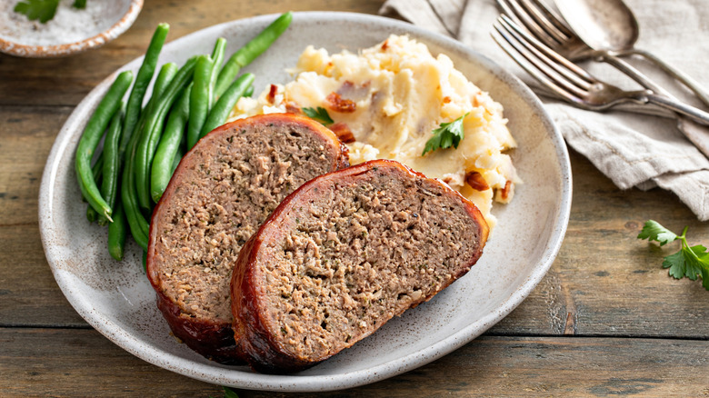 Plate of meatloaf slices, green beans, and mashed potatoes