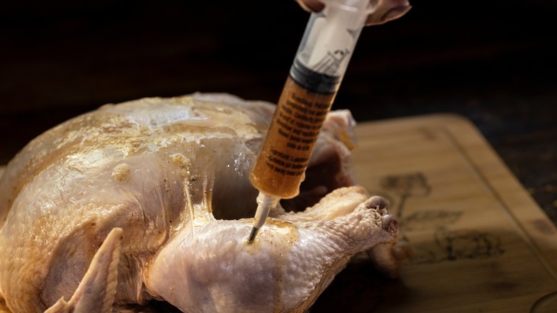 Injecting chicken meat with syringe