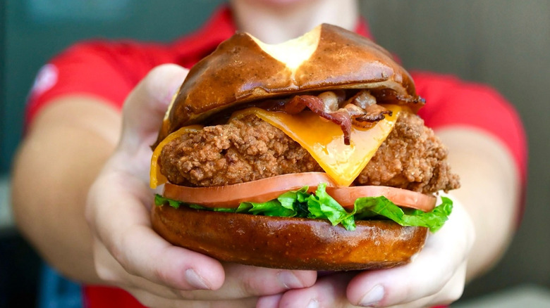 A Chick-fil-A employee holds out a chicken sandwich.