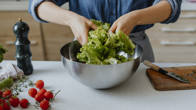 Woman's hands mixing a salad with dressing in a bowl