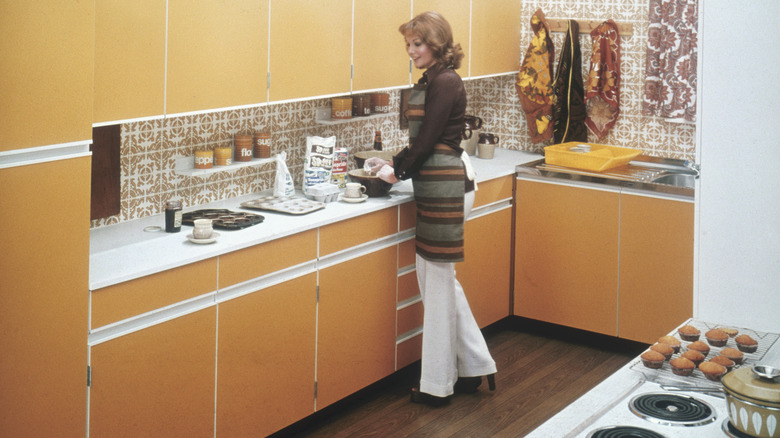 A person cooking in a 1970's-era kitchen