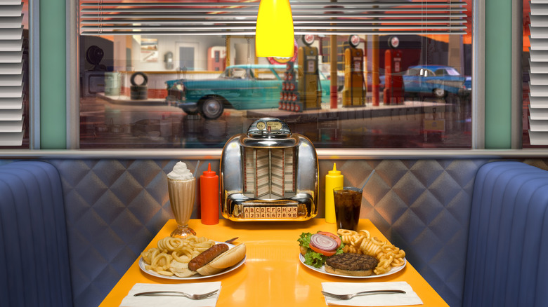 A booth at a 1950s-style diner with two meals on the table