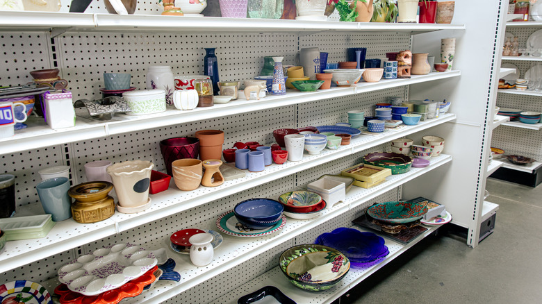 A jumble of kitchenwares sit on shelves in a thrift store