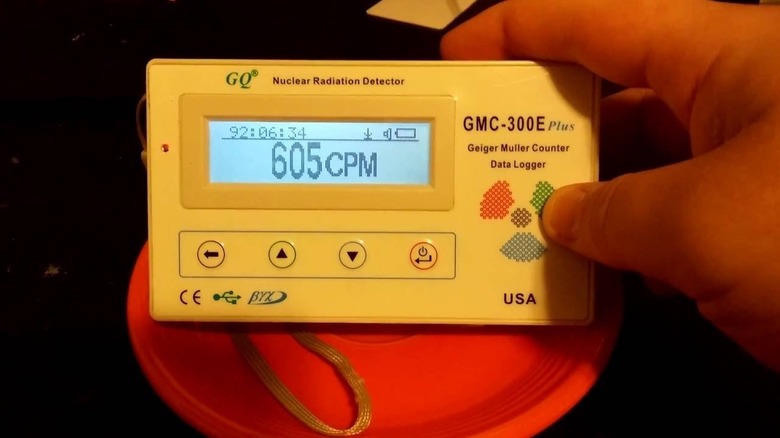 A man holds a nuclear radiation detector up to a piece of radioactive red Fiestaware