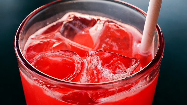 Pink soda in a glass with ice and a straw