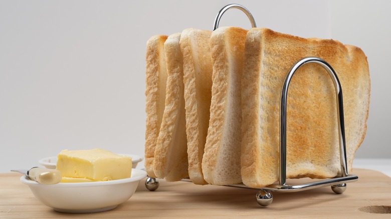 Metal toast rack with slices of toast and dish of butter