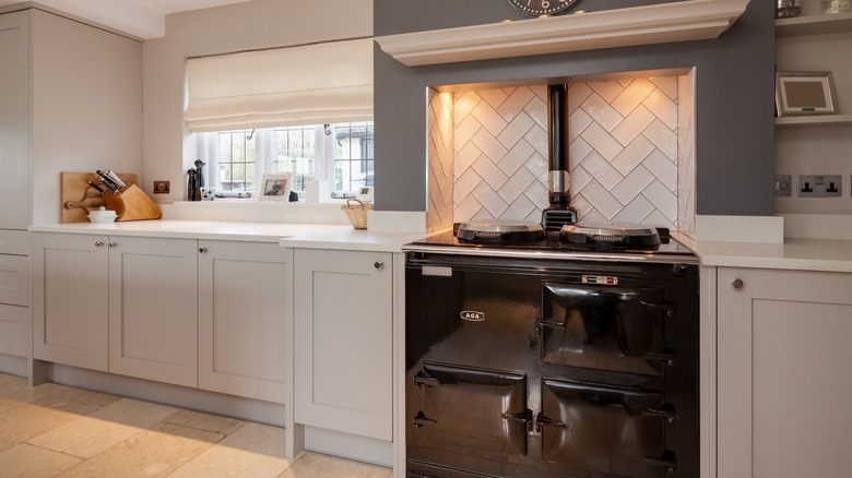 A beautiful stainless steel stove is inset into a range alcove with white-colored tile