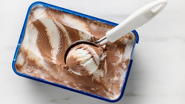 scooping vanilla and chocolate ice cream from tub