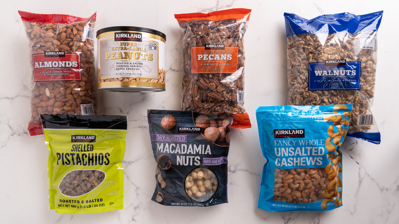 A slew of packages, bags, and cans of Kirkland nuts on a counter.