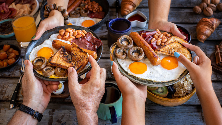 Top view of a breakfast table featuring full English breakfasts and croissants