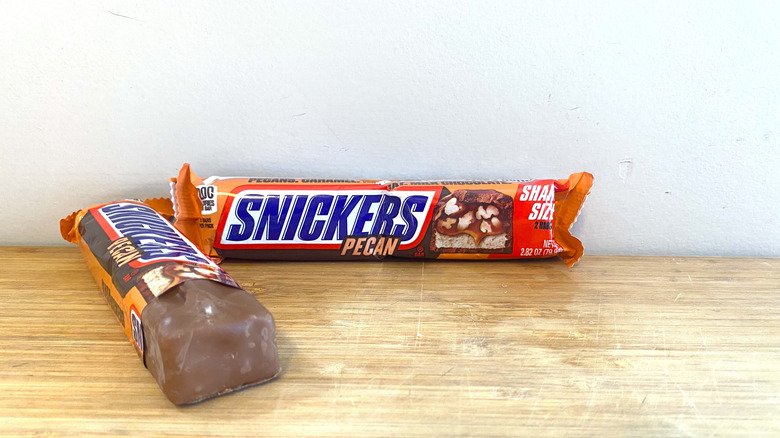 Two Snickers Pecan bars, one partially opened.